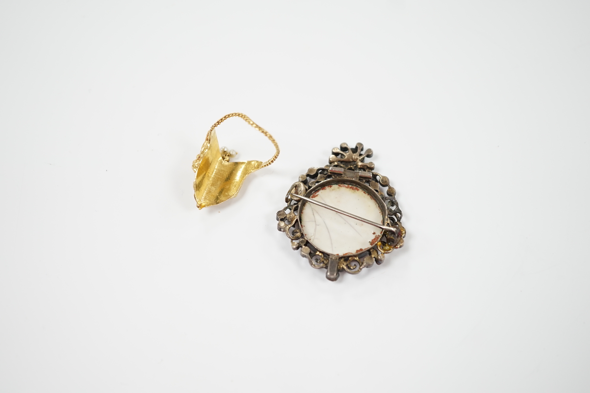 An Indian? yellow metal and gem set upfinger ring, with seed pearl cluster drop, size O and a 19th century white metal and paste set brooch with inset plaque.